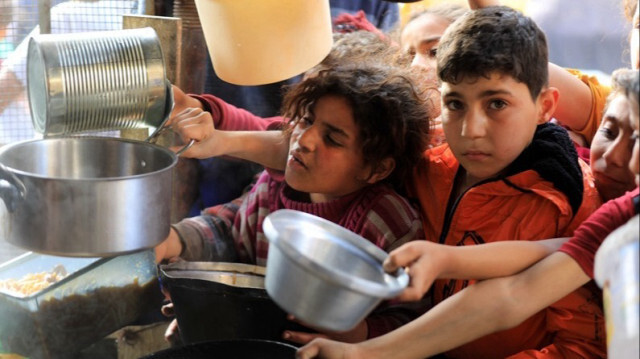 Des enfants Palestiniens tiennent des conteneurs vides pour recevoir de la nourriture, distribuée par des organisations caritatives dans la Bande de Gaza.