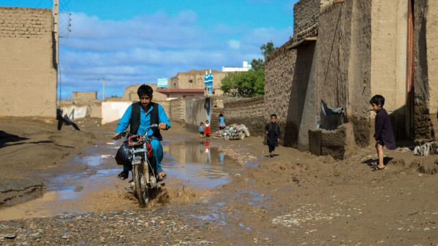 Un automobiliste afghan traverse une flaque d'eau à la suite de fortes pluies et d'inondations soudaines dans le district de Guzara, dans la province de Herat, le 15 avril 2024.
