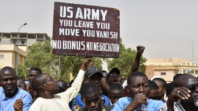 Des manifestants réagissant alors qu'un homme brandit une pancarte demandant que les soldats de l'armée américaine quittent le Niger sans négociation lors d'une manifestation à Niamey, le 13 avril 2024. Le 19 avril, les États-Unis ont accepté de retirer leurs plus de 1 000 soldats du Niger, ont indiqué des responsables, bouleversant ainsi leur position en Afrique de l'Ouest, où le pays abritait une importante base de drones.