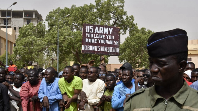 Des manifestants se rassemblent alors qu'un homme brandit une pancarte demandant que les soldats de l'armée américaine quittent le Niger sans négociation lors d'une manifestation à Niamey, le 13 avril 2024.