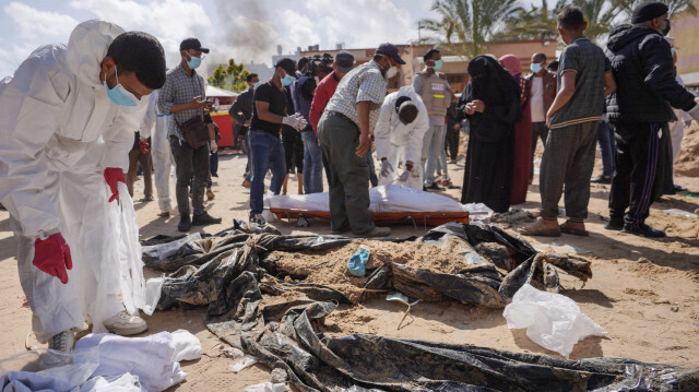 Le 21 avril 2024, des travailleurs de la santé palestiniens se tenant à côté de corps enterrés par les forces israéliennes dans l'enceinte de l'hôpital Nasser à Khan Yunis, dans le sud de la bande de Gaza, alors que les combats se poursuivent entre les militants du Hamas et les forces israéliennes dans le territoire palestinien assiégé.