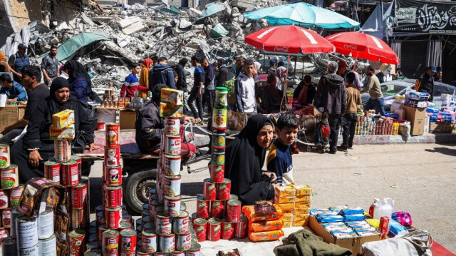 Des Palestiniens marchant sur un marché à côté de décombres de bâtiments pendant le mois de jeûne musulman du Ramadan à Rafah, dans le sud de la bande de Gaza, le 12 mars 2024, alors que les combats se poursuivent entre Israël et le groupe militant du Hamas.