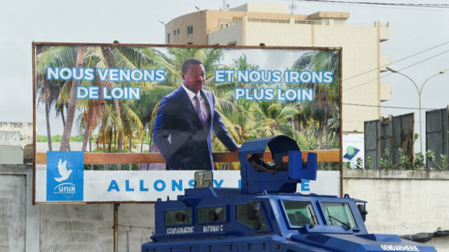 Un véhicule blindé de transport de troupes de la police est garé devant un panneau de campagne pour le président Faure Gnassingbé, candidat du parti au pouvoir Union pour la République (UNIR), et vainqueur de l'élection présidentielle qui vient de se terminer à Lomé, le 24 février 2020.