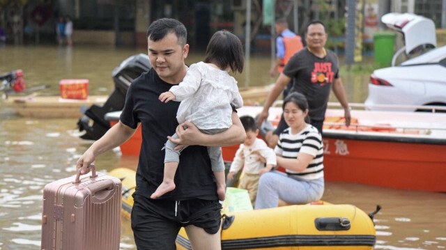 Les résidents traversent les eaux de crue après avoir été évacués d'une zone inondée à la suite de fortes pluies dans la ville de Qingyuan, dans la province du Guangdong, dans le sud de la Chine, le 22 avril 2024.
