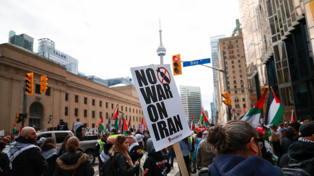 Участник акции протеста держит плакат с надписью "Нет войне с Ираном", в то время как пропалестинские демонстранты собираются у Юнион Стейшн во время митинга в Торонто, Онтарио, 21 апреля 2024 года. 