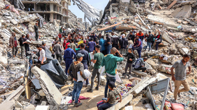 Люди собираются у разрушенного здания на месте сброса гуманитарной помощи в северной части сектора Газа 23 апреля 2024 года на фоне продолжающегося конфликта на палестинской территории между Израилем и боевой группировкой ХАМАС. 