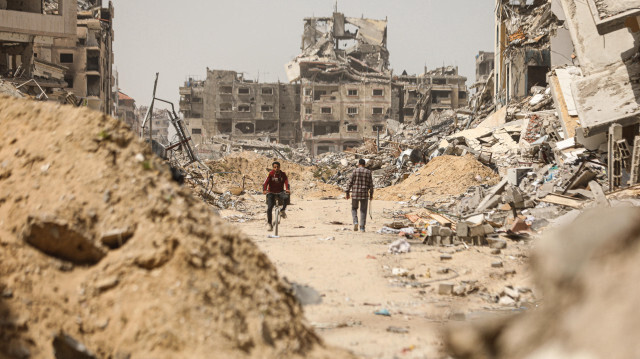 Палестинцы идут по улице, заваленной обломками разрушенных в результате израильских атак зданий, город Газа, сектор Газа, 24 апреля 2024 года.