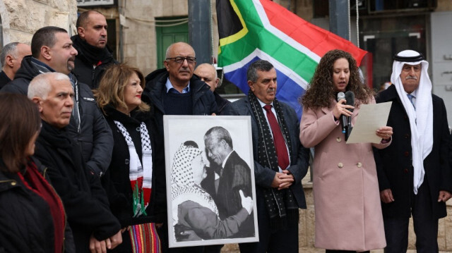 Un Palestinien tient un portrait de Yasser Arafat, chef de l'Organisation de libération de la Palestine (OLP), et de Nelson Mandela, icône de la lutte contre l'apartheid en Afrique du Sud, avant de hisser le drapeau national sud-africain devant le bâtiment de la municipalité de Bethléem, en Palestine occupée, le 12 janvier 2024. 