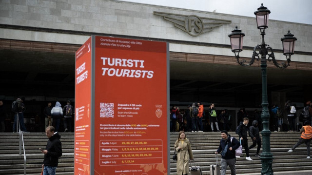Des touristes passent devant un panneau d'information à l'extérieur de la gare de Santa Lucia le 24 avril 2024 à Venise.