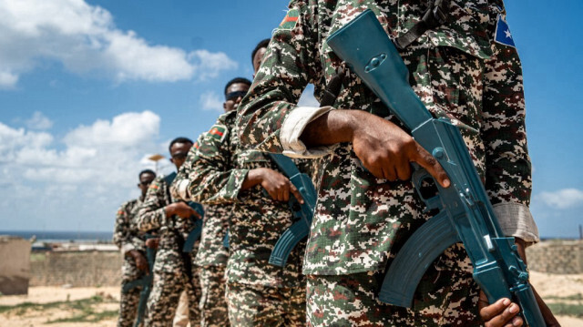 Les troupes participant au cours des officiers cadets de l'armée somalienne (SOCAC) brandissent leurs armes d'entraînement avant un exercice militaire au centre d'entraînement général Dhagabadan à Mogadiscio, le 19 mars 2024. 