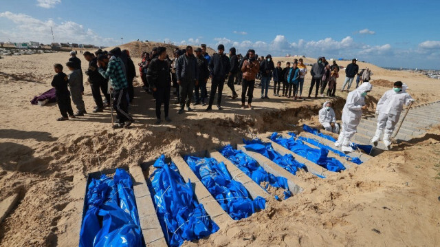 Des civils et des employés du ministère de la Santé de Gaza lors de l'enterrement des corps de martyrs Palestiniens non identifiés, dans une fosse commune à l'est de Rafah, dans le sud de la bande de Gaza, le 30 janvier 2024,