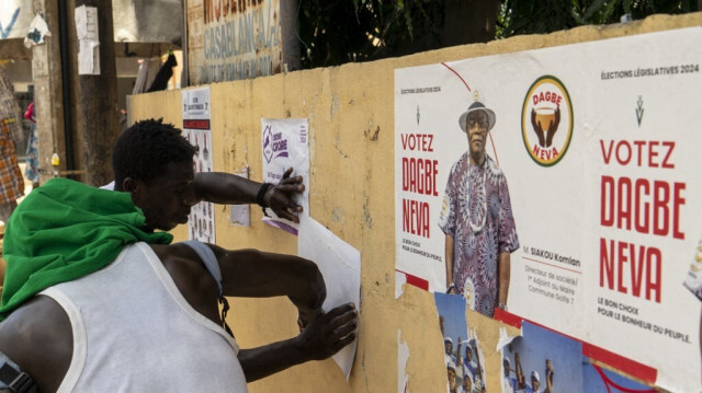 Un homme colle une affiche de campagne sur un mur, à Lomé le 24 avril 2024. 