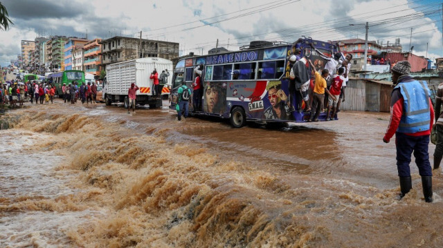 Des piétons s'accrochent à l'arrière d'un matatu (bus de transport public) pour éviter d'avoir à traverser une section de route inondée après qu'un ruisseau soit sorti de son lit pendant la nuit à la suite de fortes pluies saisonnières dans la capitale, Nairobi, le 24 avril 2024. 