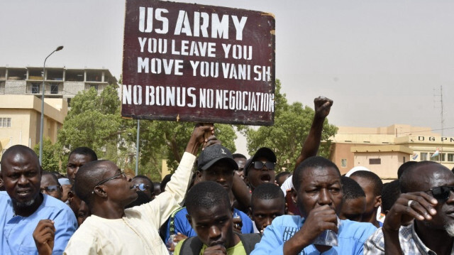 Des manifestants réagissent alors qu'un homme brandit une pancarte demandant que les soldats de l'armée américaine quittent le Niger sans négociation lors d'une manifestation à Niamey, le 13 avril 2024.