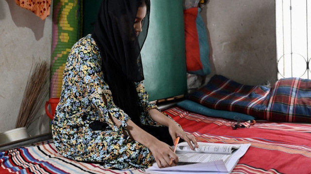 Lamia Akter étudie sur son lit chez elle, après l'annulation des cours à l'école en raison de la chaleur, à Dhaka le 25 avril 2024. 