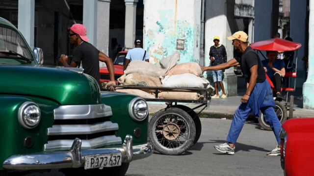 Deux hommes poussent une brouette de déchets dans une rue de La Havane, le 18 mars 2024.