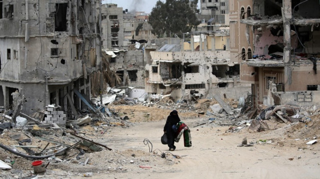 Une femme palestinienne portant quelques affaires marche dans un quartier dévasté par les bombardements israéliens à Khan Yunis, dans le sud de la bande de Gaza, le 25 avril 2024.