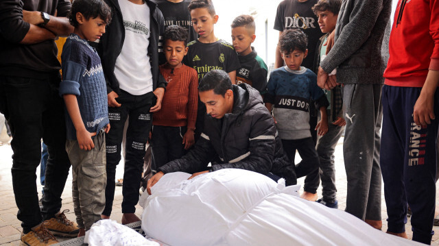 Des personnes en deuil se tenant près des corps d'un adulte et d'un enfant tués lors d'un bombardement israélien, devant la morgue d'un hôpital à Rafah, dans le sud de la bande de Gaza, le 27 avril 2024, alors que le conflit entre Israël et le groupe militant du Hamas se poursuit.
