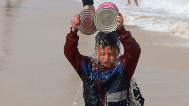 Un garçon palestinien déplacé se rafraîchit à la plage pour échapper à la chaleur torride dans les tentes du camp de Rafah, dans le sud de la bande de Gaza, le 26 avril 2024, dans le cadre du conflit actuel entre Israël et le groupe militant palestinien Hamas.