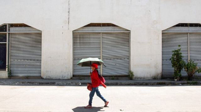 Une femme s'abrite du soleil avec un parapluie par temps chaud à Manille le 28 avril 2024.