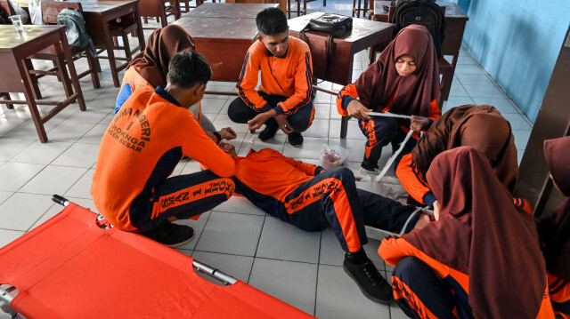 Des élèves de collège s'occupant d'un camarade jouant le rôle d'une victime blessée alors qu'ils participent à un exercice de simulation de tremblement de terre et de tsunami dans le cadre d'un programme d'éducation aux catastrophes à Lhoknga, dans la province d'Aceh, le 26 avril 2024.
