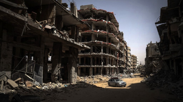 Une voiture roule sur une route bordée de bâtiments détruits à Khan Yunis, dans le sud de la bande de Gaza, le 23 avril 2024.