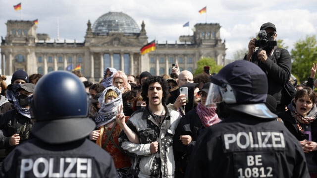 Des manifestants se tiennent devant le bâtiment du Reichstag abritant le Bundestag pendant que des officiers de police évacuent le campement de manifestants pro-palestiniens installés près de la Cour suprême fédérale à Berlin, en Allemagne, le 26 avril 2024.