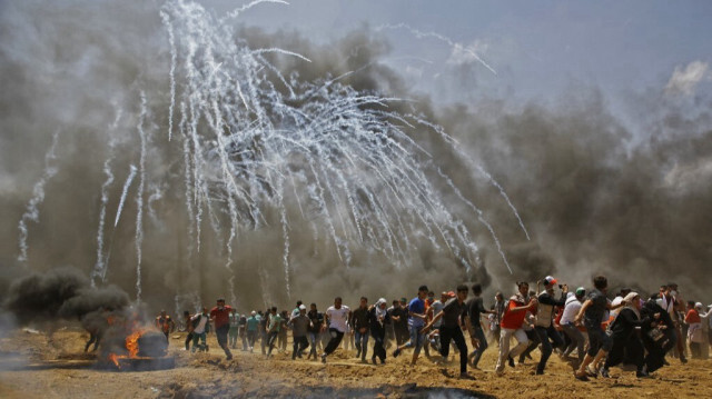 Des Palestiniens fuient les gaz lacrymogènes tirés par l'armée d'occupation israélienne près de la frontière de la bande de Gaza, à l'est de Jabalia, le 14 mai 2018. 