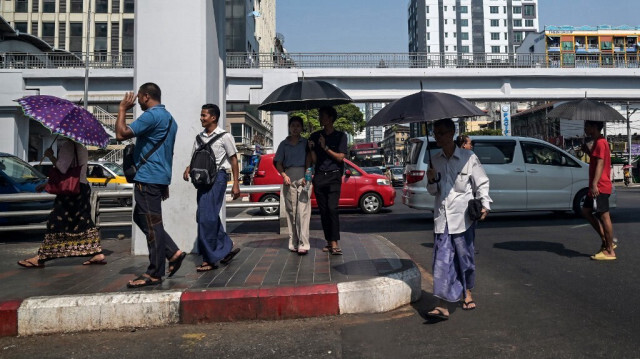 Les gens marchent sous un parapluie pour se protéger du soleil lors d'une vague de chaleur à Yangon le 2 avril 2024.