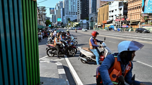 Les chauffeurs de taxi à moto attendent les clients lors d'une journée chaude à une intersection de la circulation à Bangkok le 29 avril 2024.