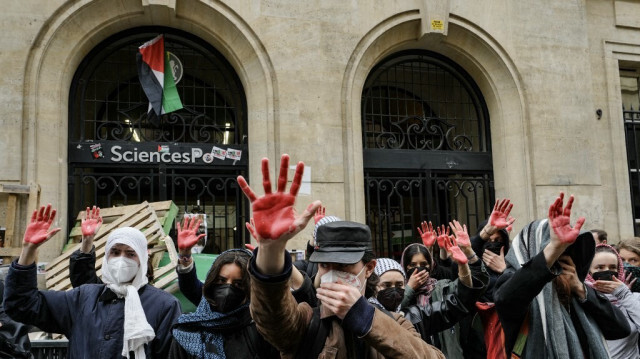 Des étudiants manifestent avec leurs mains recouvertes de peinture rouge symbole de sang devant l'Institut d'études politiques (Sciences Po Paris) en soutien aux Palestiniens, à Paris, le 26 avril 2024.
