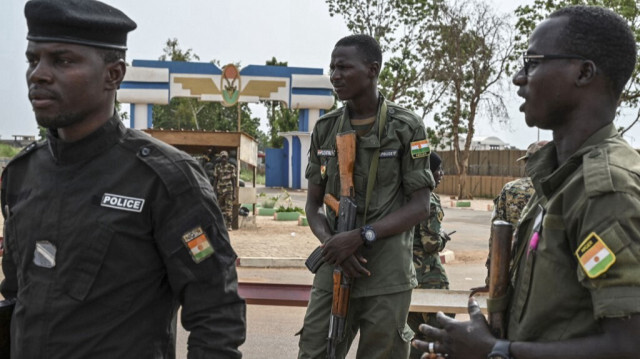 Des agents de la police nationale nigérienne montent la garde alors que des partisans du Conseil national de sauvegarde de la patrie (CNSP) manifestent devant la base aérienne nigéro-française de Niamey, le 30 août 2023, pour exiger le départ de l'armée française du Niger.