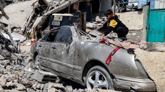 Un garçon dégage les décombres d'un véhicule lourdement endommagé à l'extérieur d'un bâtiment détruit à Rafah, dans le sud de la bande de Gaza, le 5 avril 2024.