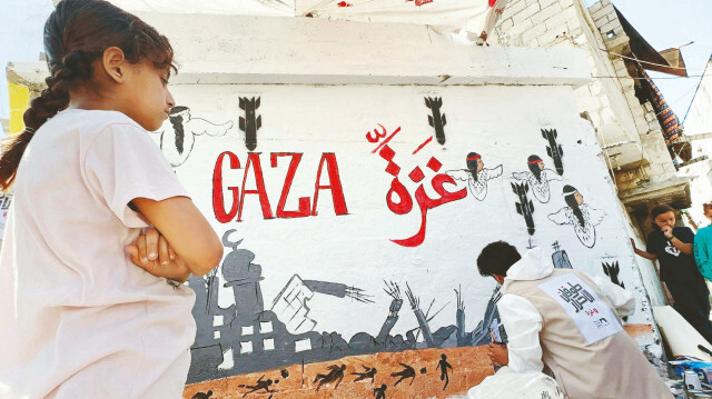 5 Nisan ‘Filistinli Çocuklar Günü’ dolayısıyla Refah’ta buluşan Gazzeli ressamlar, İsrail saldırıları sonucu hayatını kaybeden binlerce çocuğu anmak için duvara grafiti çizdi.