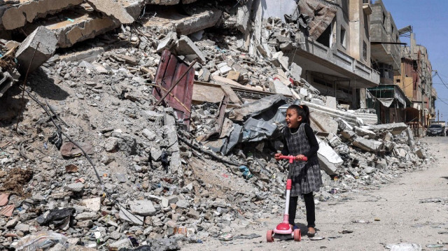 Une jeune fille passe en scooter devant les décombres d'un bâtiment détruit à Rafah, dans le sud de la bande de Gaza, le 5 avril 2024.