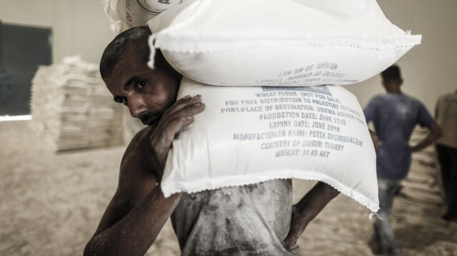 Des Palestiniens déchargent des sacs d'aide dans un centre de distribution alimentaire des Nations unies dans le camp de réfugiés de Jabalia, dans le nord de la bande de Gaza, le 8 août 2018.