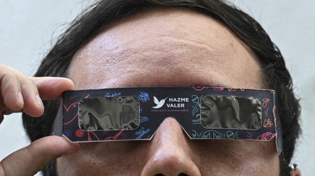 Un employé du secrétariat à la sécurité citoyenne montre des lunettes de soleil spéciales pour observer la prochaine éclipse solaire, qui seront vendues au public au musée de la police de Mexico le 4 avril 2024.