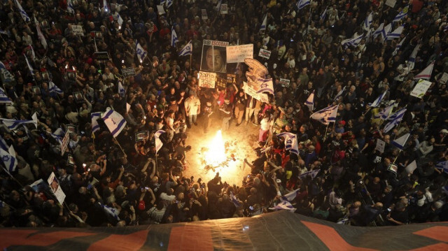 Des parents et des sympathisants des otages israéliens détenus à Gaza brandissent des pancartes et des drapeaux israéliens lors d'une manifestation devant le ministère de la Défense à Tel Aviv, le 6 avril 2024.