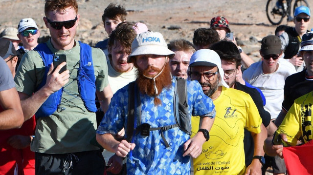 Le coureur britannique Russ Cook (C) est rejoint par des supporters lors de la dernière étape de son défi de 16 000 kilomètres à travers le continent africain, du Cap Agulhas en Afrique du Sud au Cap Angela en Tunisie, afin de collecter des fonds pour des œuvres caritatives, près du Cap Angela, au nord-est de Tunis, le 7 avril 2024.