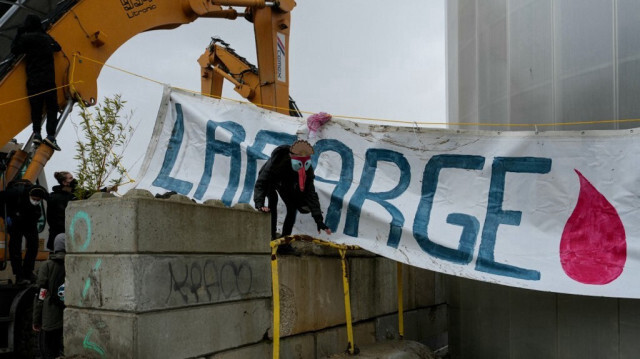 Un membre des Soulevements de la Terre (SLT), porte un masque de dindon, en référence à l'expression française "Les dindons de la farce", ici transformée en jeu de mots sur Lafarge "Les dindons de Lafarge", lors d'un rassemblement devant la centrale à béton Lafarge à Paris, le 10 décembre 2023, pour protester contre le béton et la métropolisation.