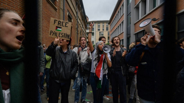 Des étudiants, derrière et devant une grille d'entrée verrouillée, assistent à un rassemblement pro-palestinien à l'université Sciences Po de Toulouse, dans le sud de la France, le 30 avril 2024.
