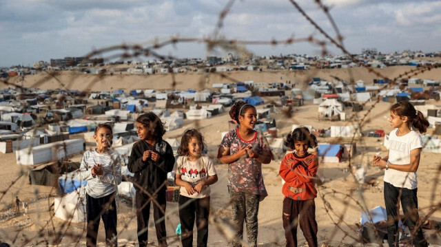 Des enfants se tiennent derrière des barbelés le long d'une pente près d'un camp abritant des Palestiniens déplacés à Rafah, dans le sud de la bande de Gaza, le 30 avril 2024.