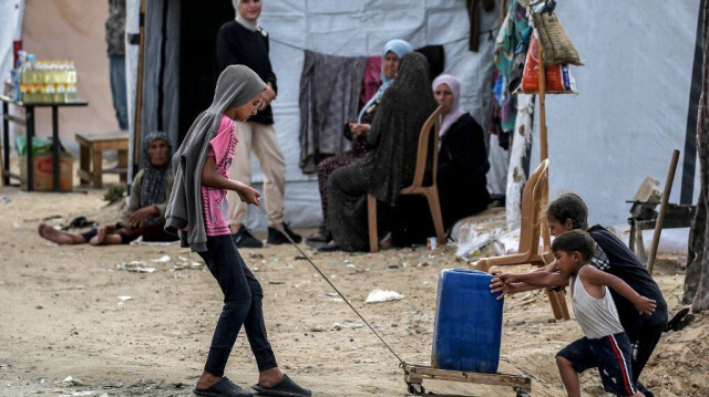 Des enfants montent un jerrycan sur une pente dans un camp abritant des Palestiniens déplacés à Rafah, dans le sud de la bande de Gaza, le 30 avril 2024.