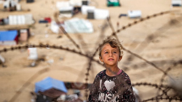 Un enfant se tient derrière des barbelés le long d'une pente près d'un camp abritant des Palestiniens déplacés à Rafah, dans le sud de la bande de Gaza, le 30 avril 2024.