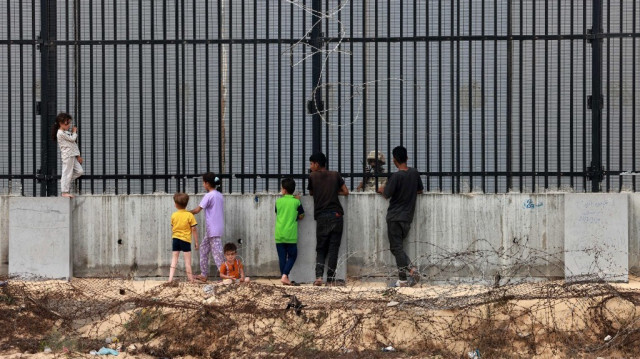 Des enfants palestiniens déplacés de force par les conséquences de la guerre dévastatrice mené par Israël discutent avec un soldat égyptien qui monte la garde à la frontière entre l'Égypte et Rafah, dans le sud de la bande de Gaza, le 26 avril 2024.