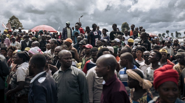 Des personnes déplacées par la guerre se rassemblent pour regarder une délégation de fonctionnaires de l'ONU visitant le camp de déplacés de Bulengo, près d'une ligne de front à la périphérie ouest de Goma, le 17 avril 2024. 