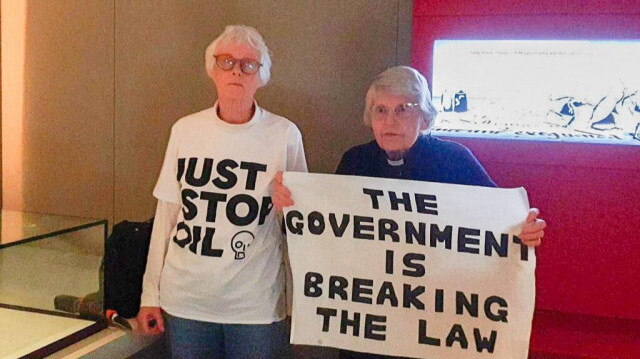 Les activistes Révérende Sue Parfitt (à droite) et Judy Bruce tenant une banderole lors d'une tentative de briser la vitrine protégeant la copie de la Magna Carta dans la Galerie des Trésors de la British Library à Londres le 10 mai 2024.