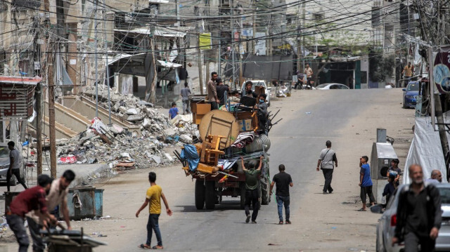 Des hommes montent à l'arrière d'un camion chargé de meubles et d'autres objets alors qu'ils fuient vers Khan Yunis, à Rafah, dans le sud de la bande de Gaza, le 11 mai 2024. 