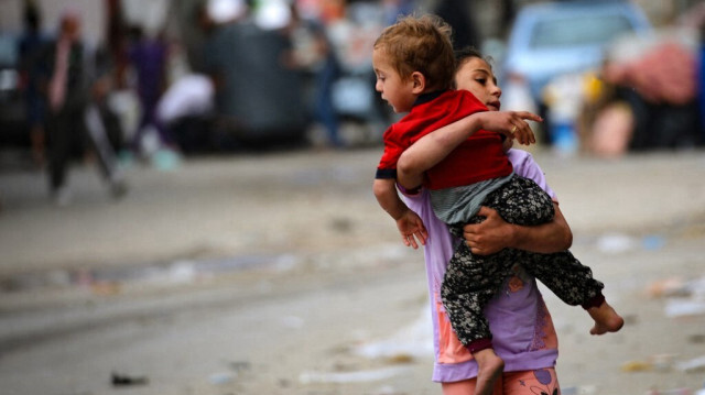 Une jeune fille palestinienne porte un enfant en bas âge alors que les gens fuient Rafah, dans le sud de la bande de Gaza, pour se rendre dans un endroit plus sûr, le 11 mai 2023.