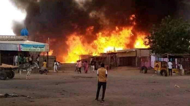 Un homme se tenant debout alors qu'un incendie fait rage dans un marché aux bestiaux à al-Fasher, la capitale de l'État soudanais du Darfour-Nord, le 1er septembre 2023, à la suite d'un bombardement par les forces paramilitaires de soutien rapide (RSF). 